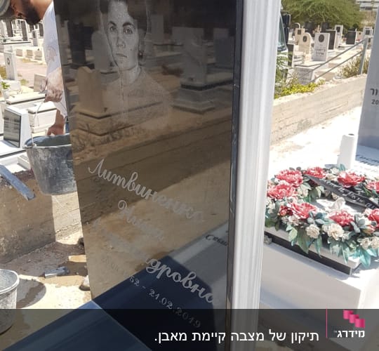 מצבה שחורה עם חריטה ותמונה בבית קברות